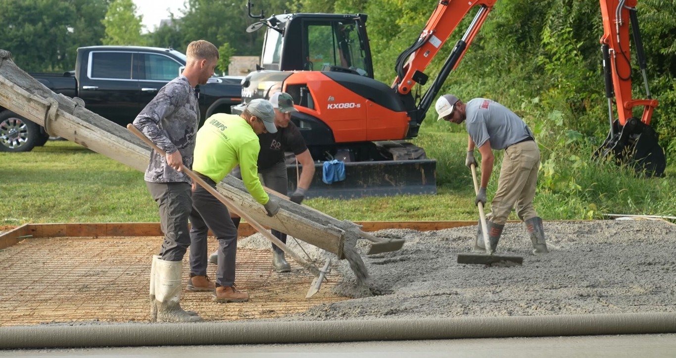Workers performing precision concrete grading and finishing